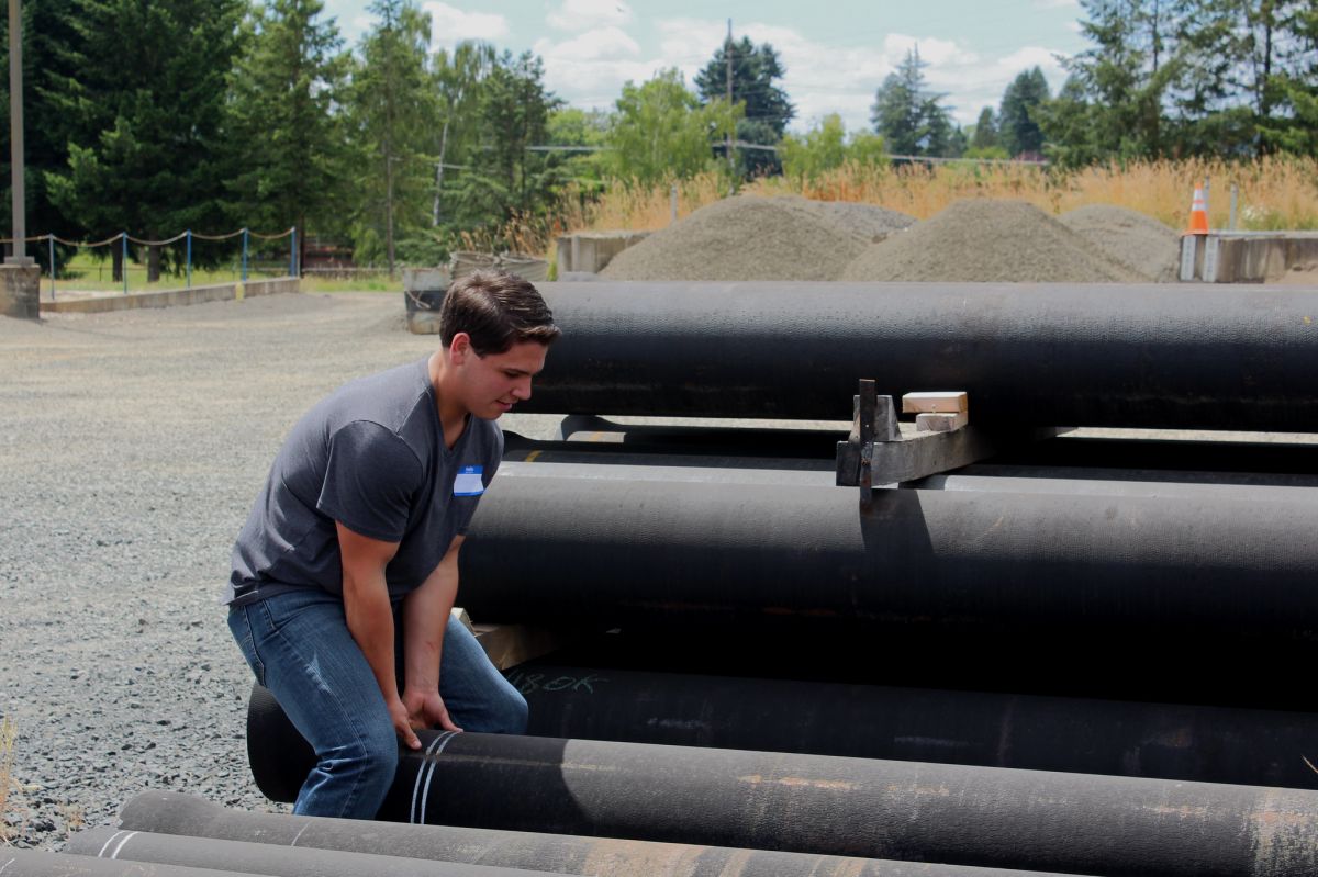 Kyle Cool, intern at Fackler Construction, lifts a water pipe for a large building project at McMinnville Water & Light